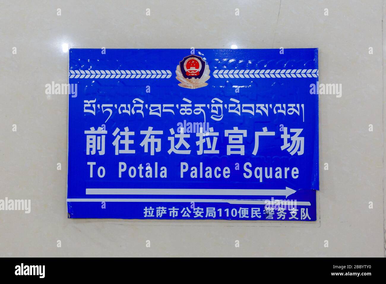 Blue sign in an underpass, pointing the way towards the famous Potala Palace. The sign is trilingual: english, mandarin and tibetan. Stock Photo