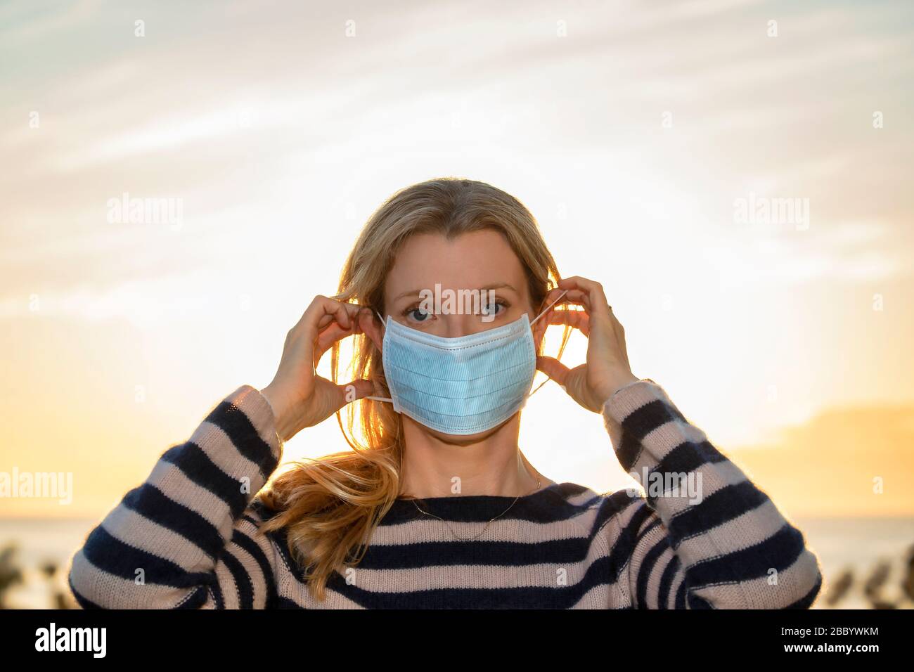 Woman putting on a protective face mask Stock Photo