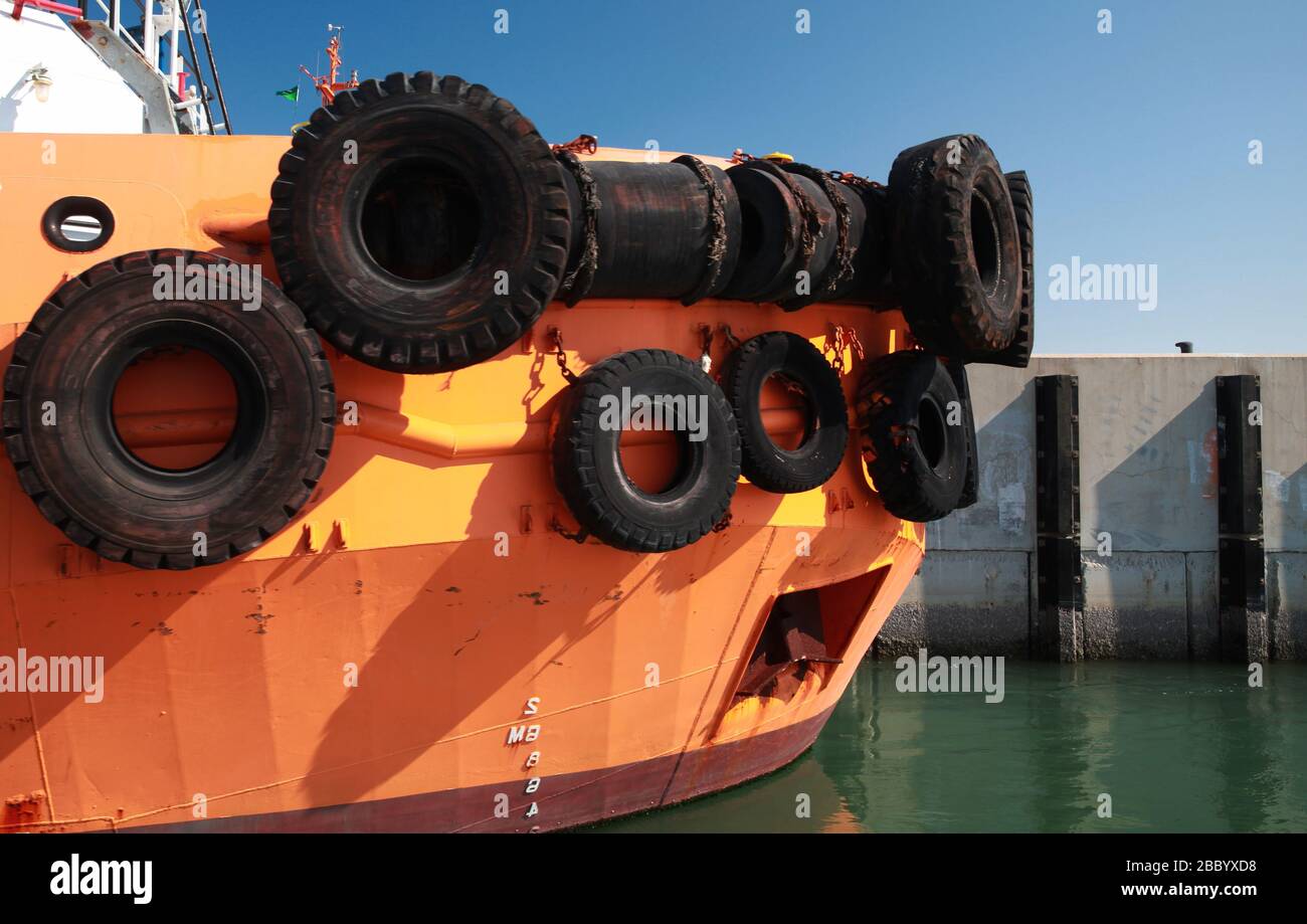 Bow of a tug boat with  bright orange hull moored in a port Stock Photo