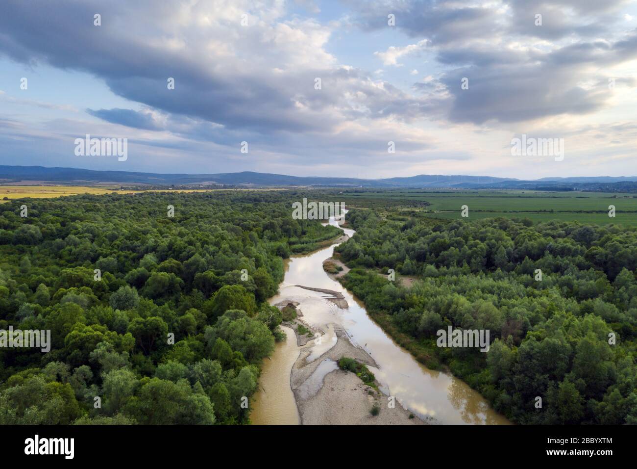 Flight through majestic river Dnister and lush green forest at sunset ...