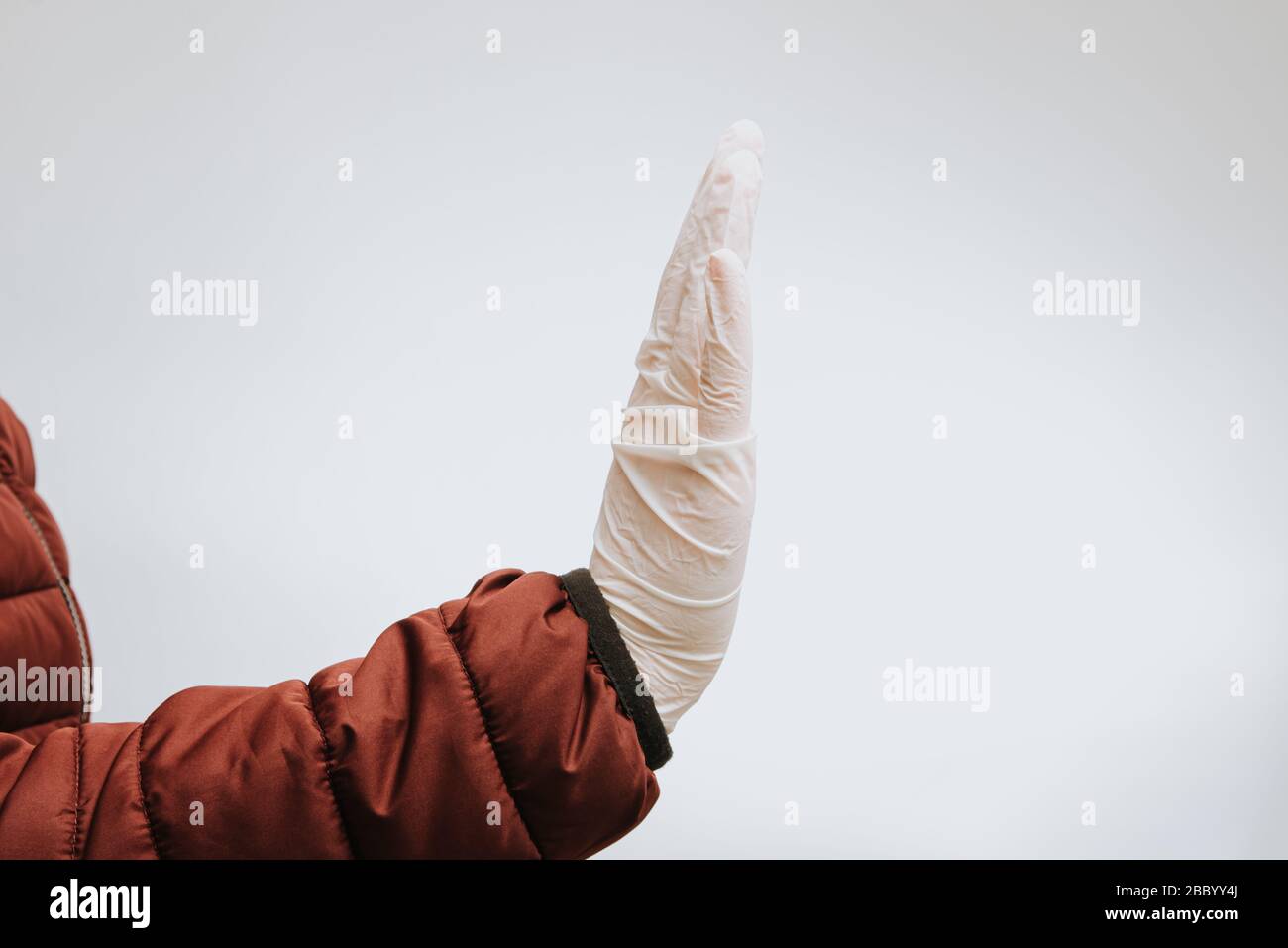 hand in medical gloves gesturing stop to coronavirus covid-19 with text on white background Stock Photo