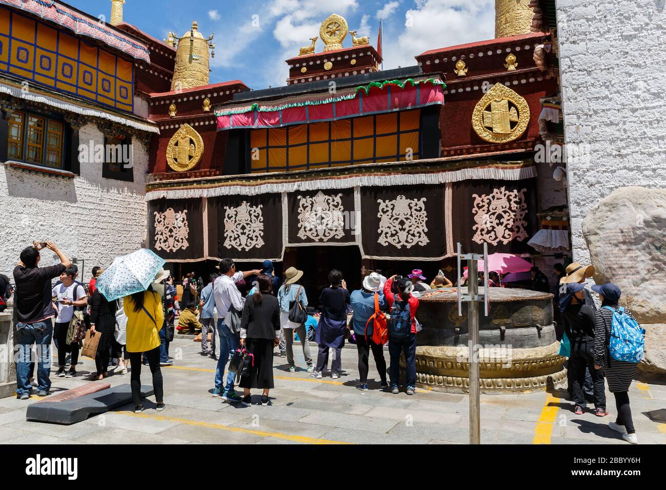 Tourists and pilgrims standing in front of Jokhang temple, admiring the beauty of the famous golden colored rooftop. Stock Photo
