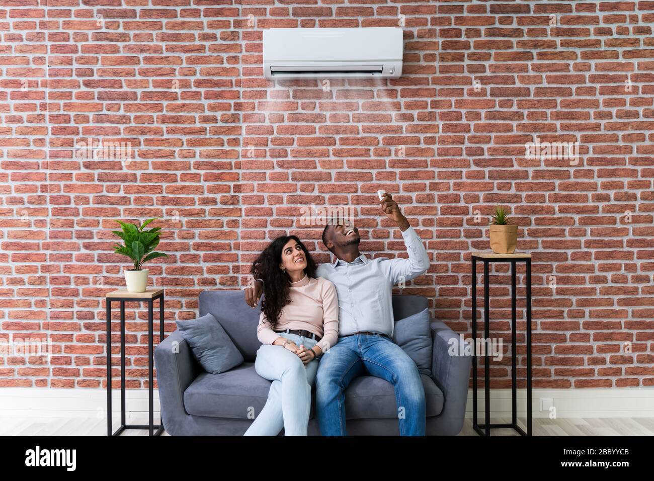 Young Happy Couple Sitting On White Sofa Stock Photo