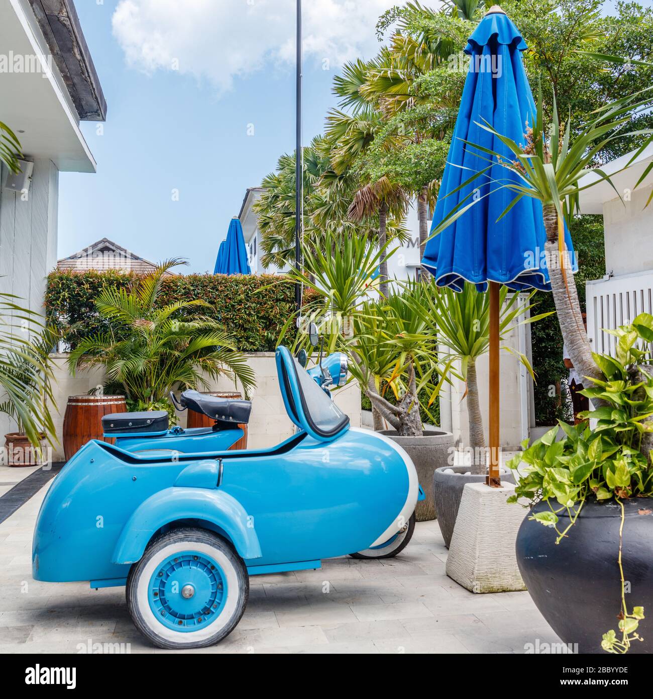 Brand new sky blue stylish moped with a sidecar. Blue sun umbrellas.  Square image. Stock Photo