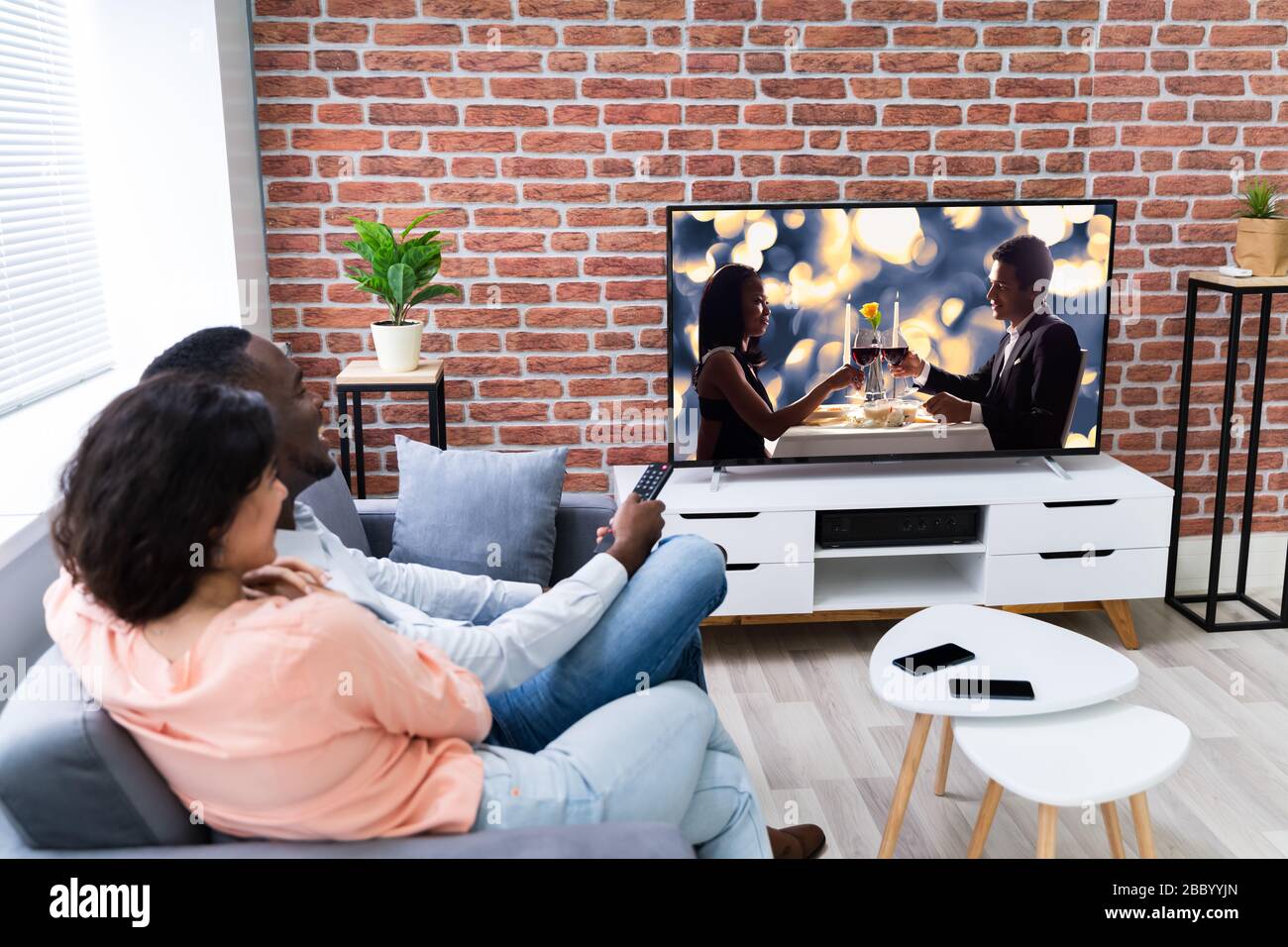 Rear View Of A Couple Watching Movie On Television At Home Stock Photo