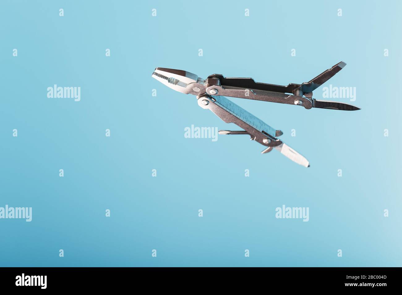 The multitool multi-function tool hovers on a blue background. The concept of an expanded multi-tool with free space. Stock Photo