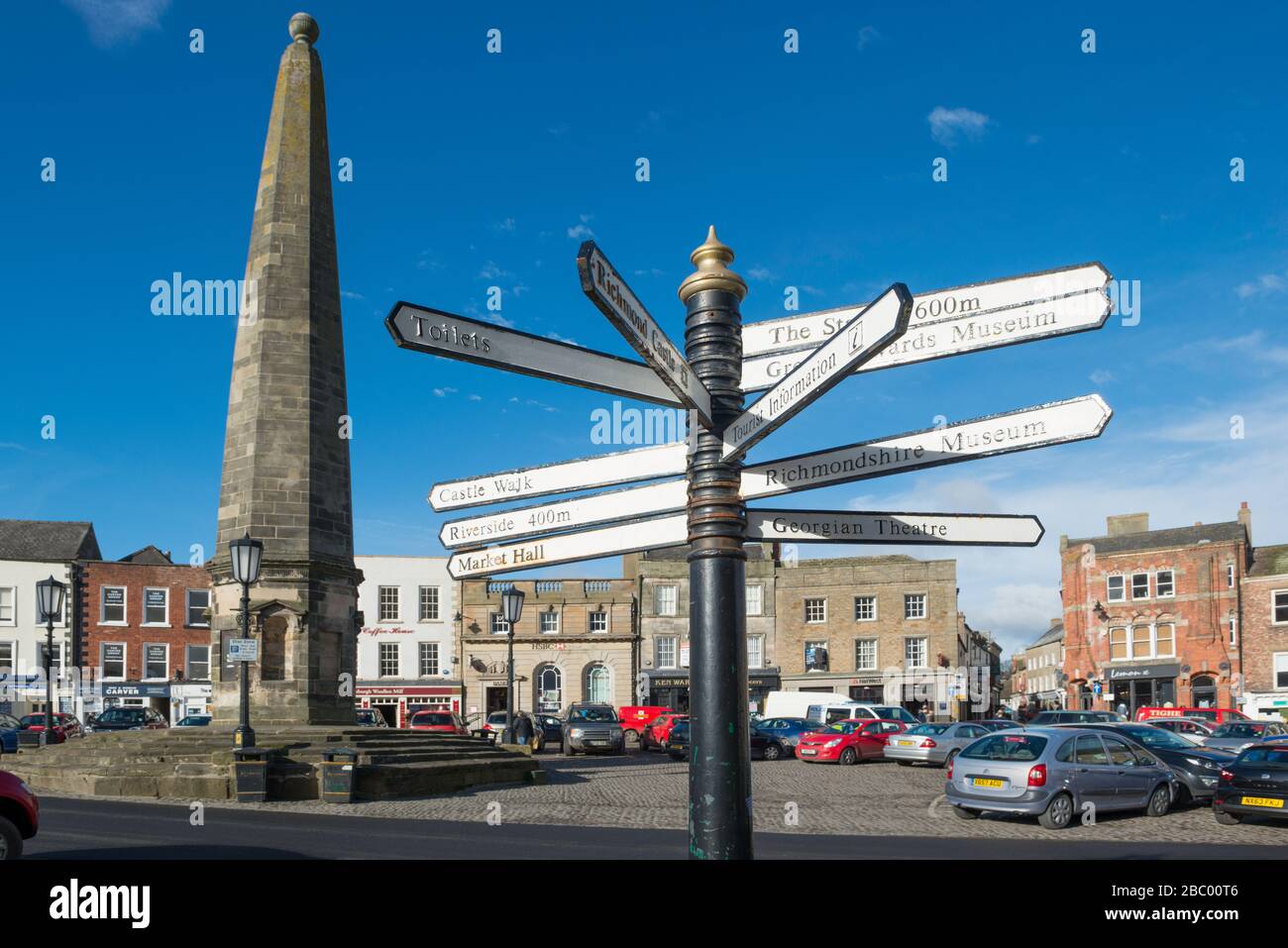 direction indicator to attractions and the substantial stone obelisk or market cross in the centre Richmond in North Yorkshire Stock Photo