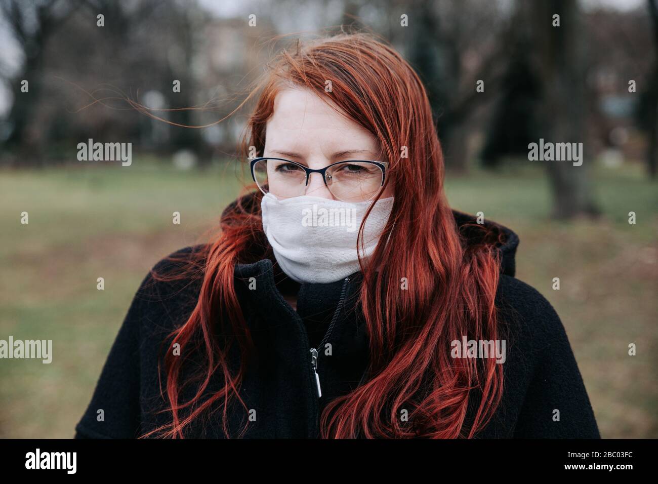Cold and flu. Woman with a medical face mask in park outdoor Stock Photo