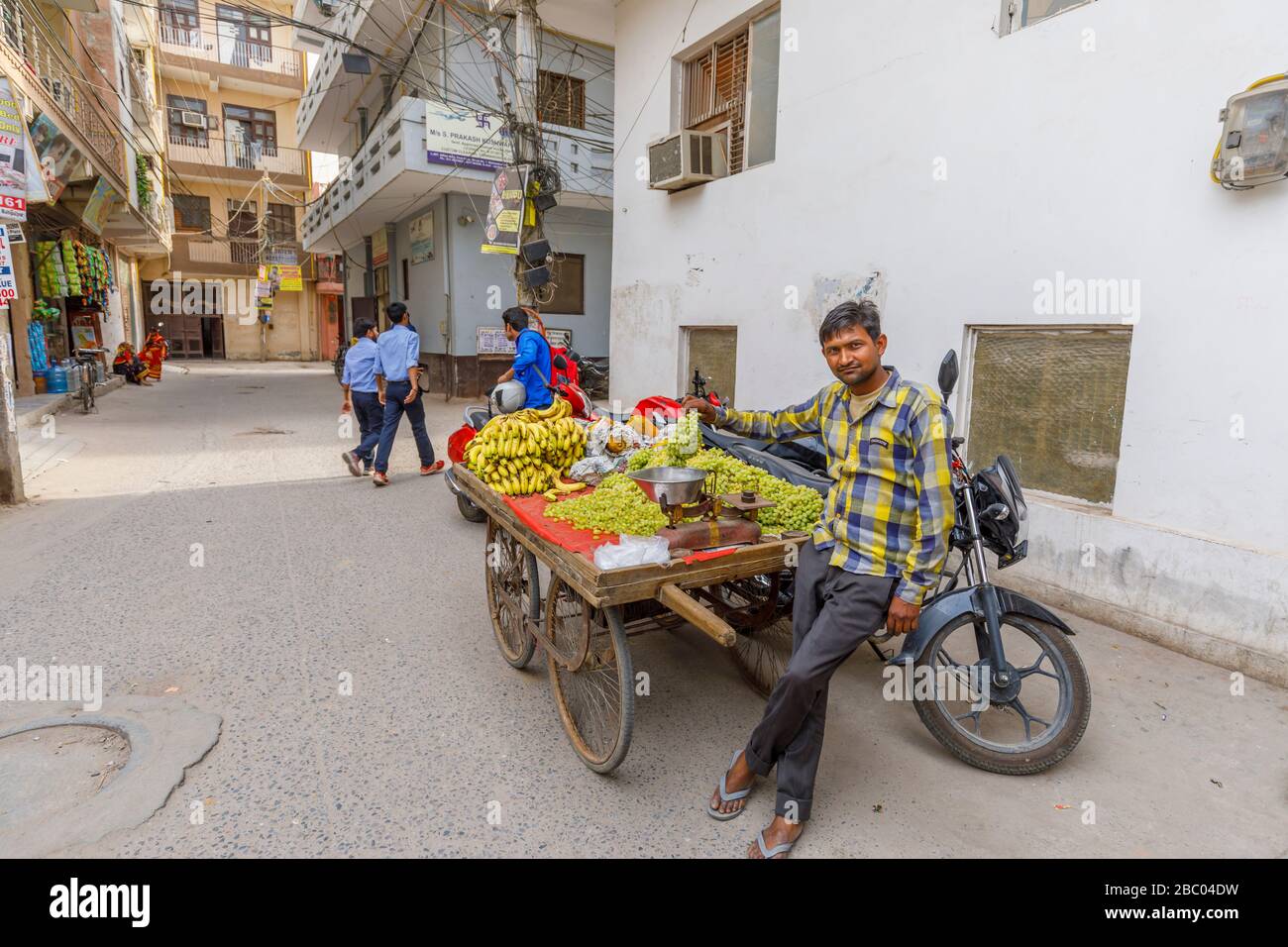 Local man selling fruit from a roadside barrow: street scene in Mahipalpur district, a suburb near Delhi Airport in New Delhi, capital city of India Stock Photo