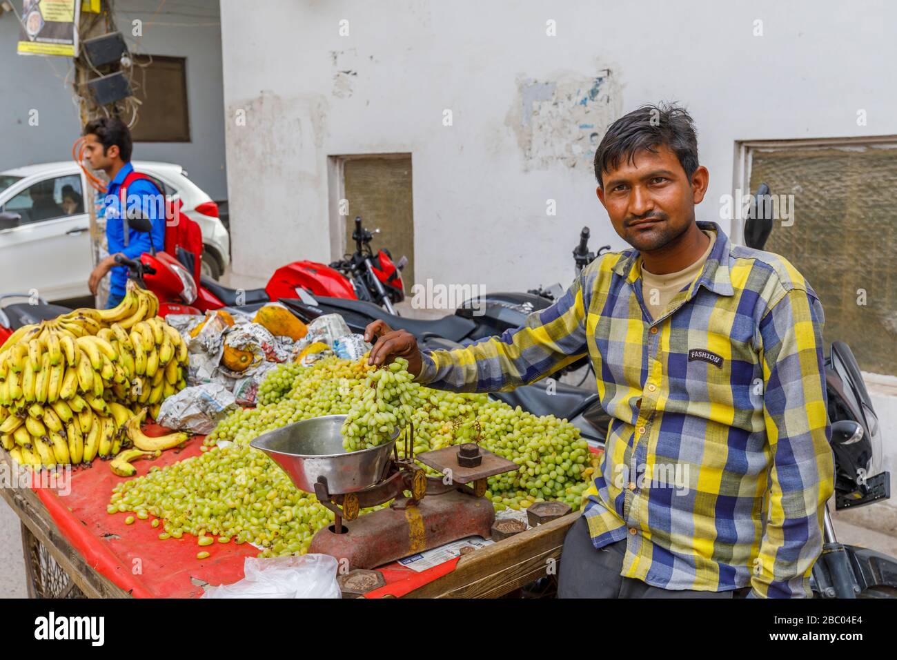 Local man selling fruit from a roadside barrow: street scene in Mahipalpur district, a suburb near Delhi Airport in New Delhi, capital city of India Stock Photo