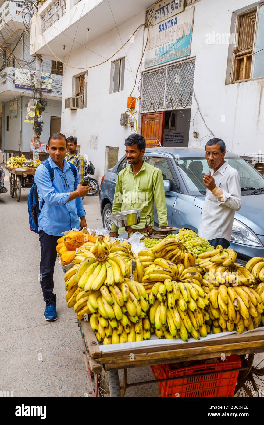 Local man selling fruit from a roadside barrow: street scene in Mahipalpur district, a suburb near Delhi Airport in New Delhi, capital city of India Stock Photo