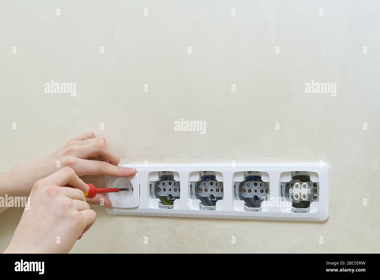 Electrician install outlets on beige wall with eu standards Stock Photo