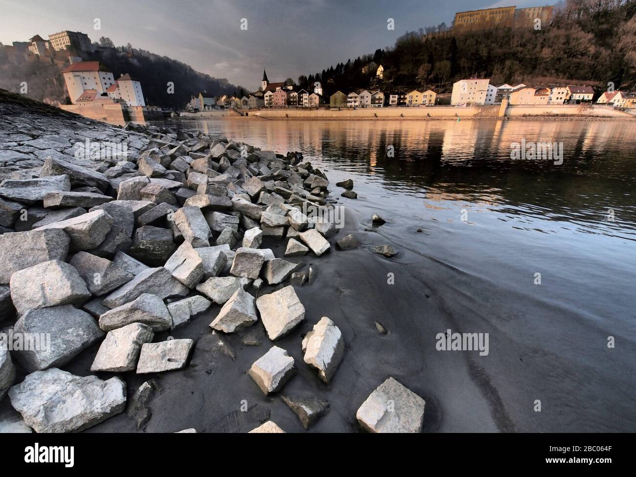 Stones of the bank reinforcement at low water at the confluence of the Inn and Danube in Passau. In the background the Ilz town and the fortress Oberhaus. [automated translation] Stock Photo