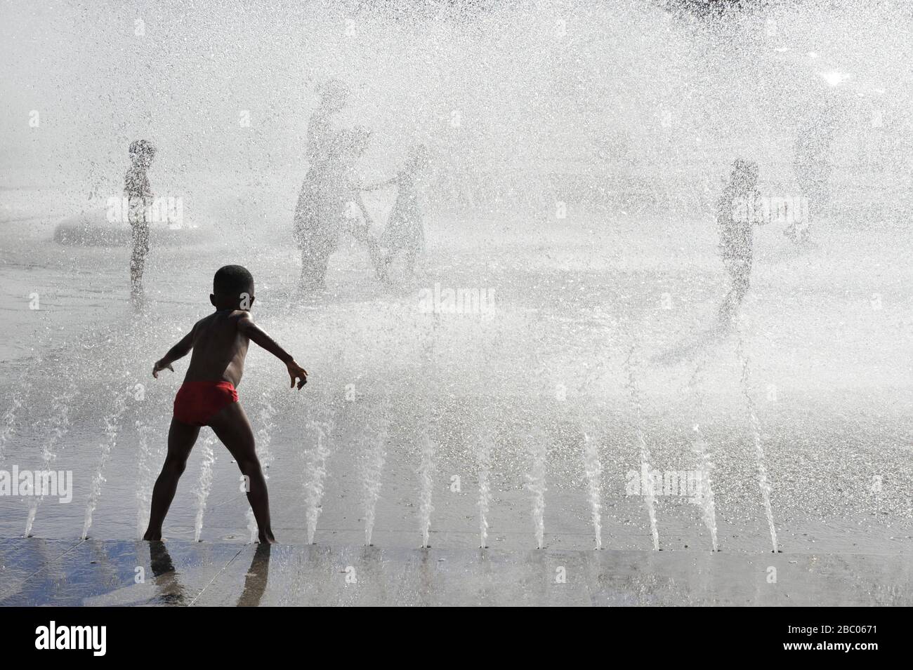 On a hot summer's day, children seek cooling in the spray of the Stachus fountain in downtown Munich. [automated translation] Stock Photo
