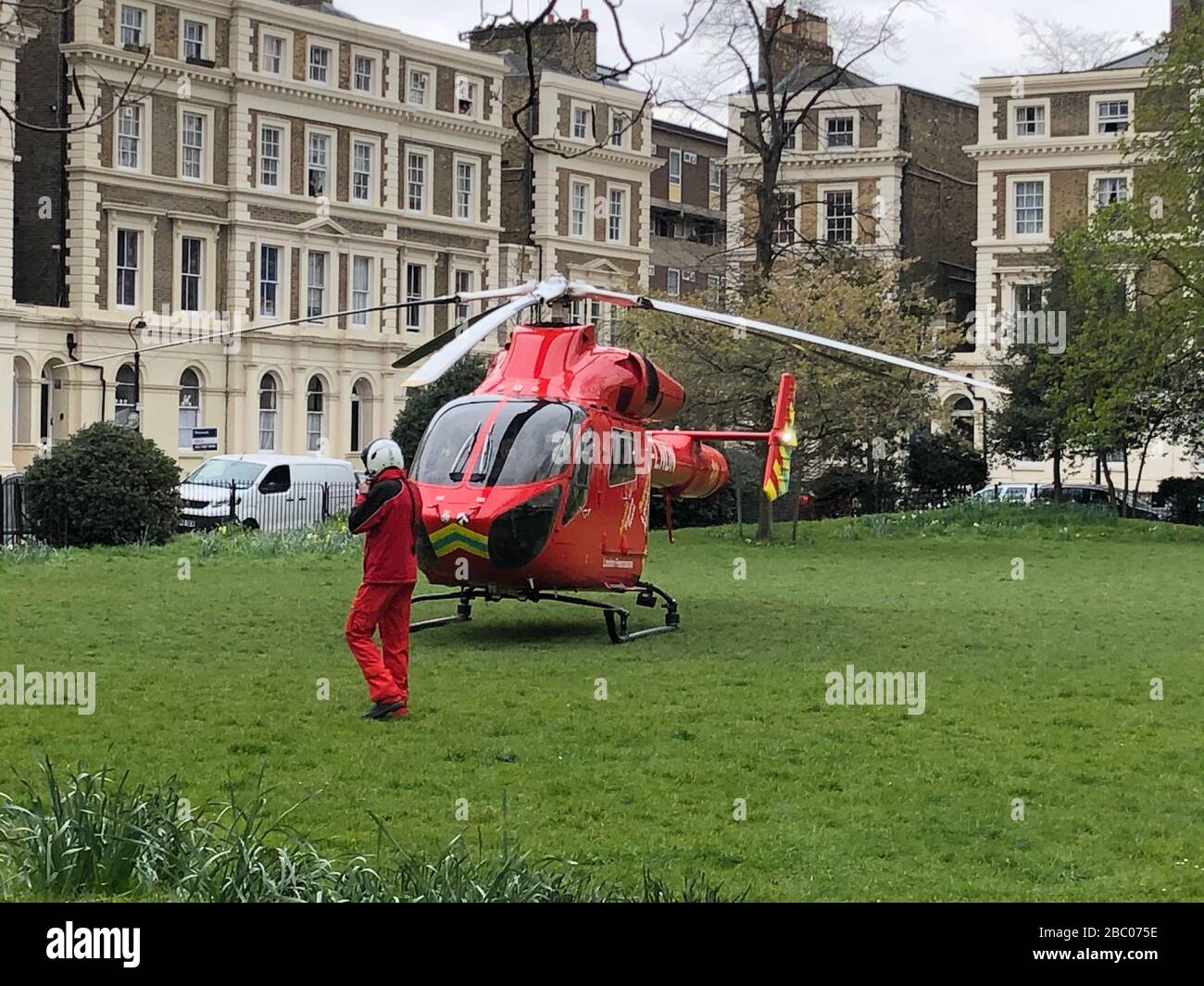 London, UK. 1st April 2020. London's air ambulance G-LNDN helicopter lands in Albert Square green area. Stock Photo