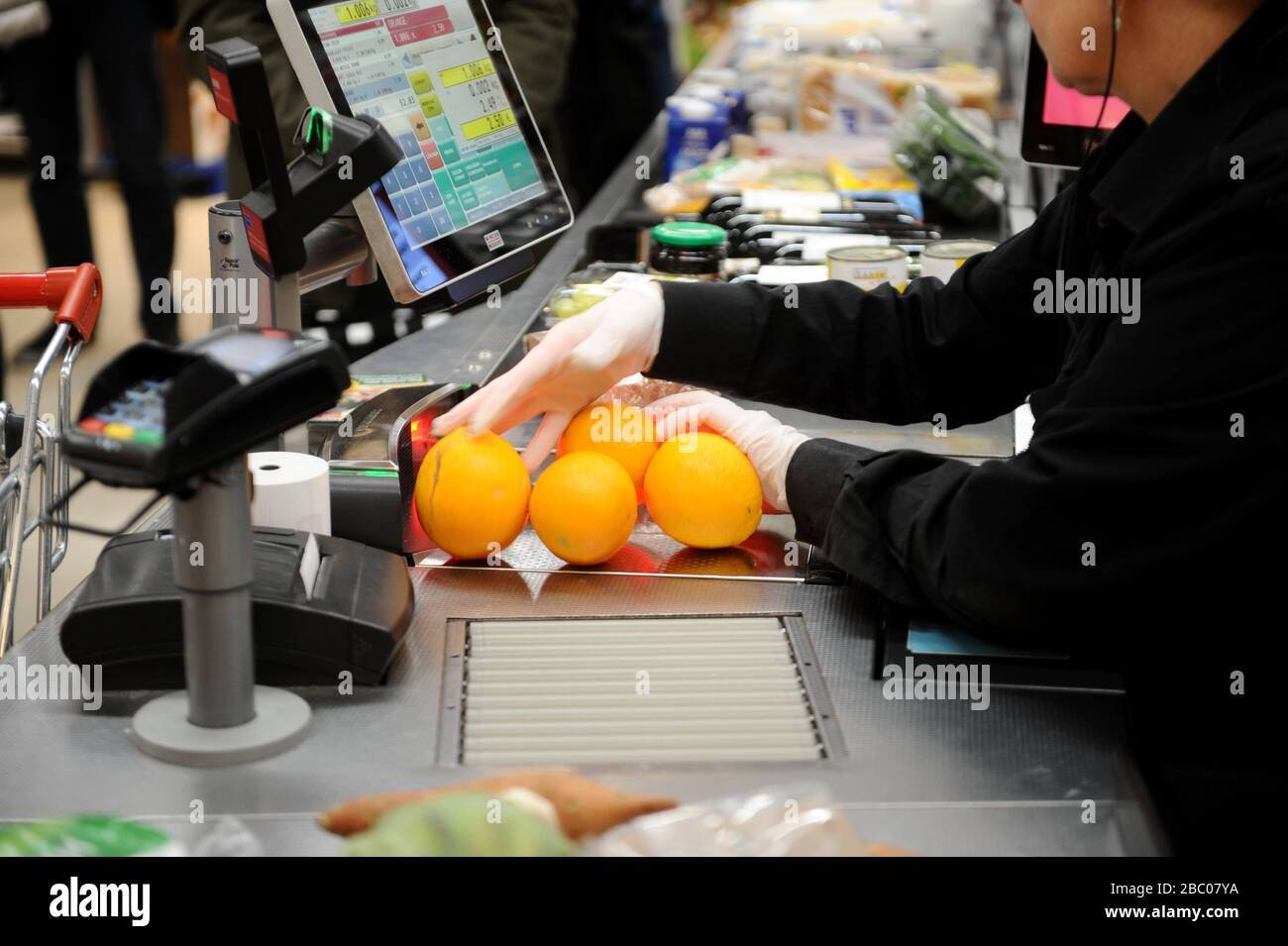 Food shopping in times of the Corona pandemic: in the picture a cashier with protective gloves at work in a branch of the supermarket chain Rewe in Obergiesing. [automated translation] Stock Photo