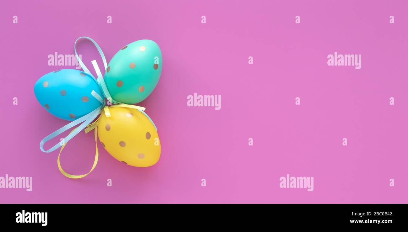Easter eggs on pink background, paschal gift card with text space. Art design decoration. Colorful paschal egg, holiday pattern, mockup. Wide panorama Stock Photo