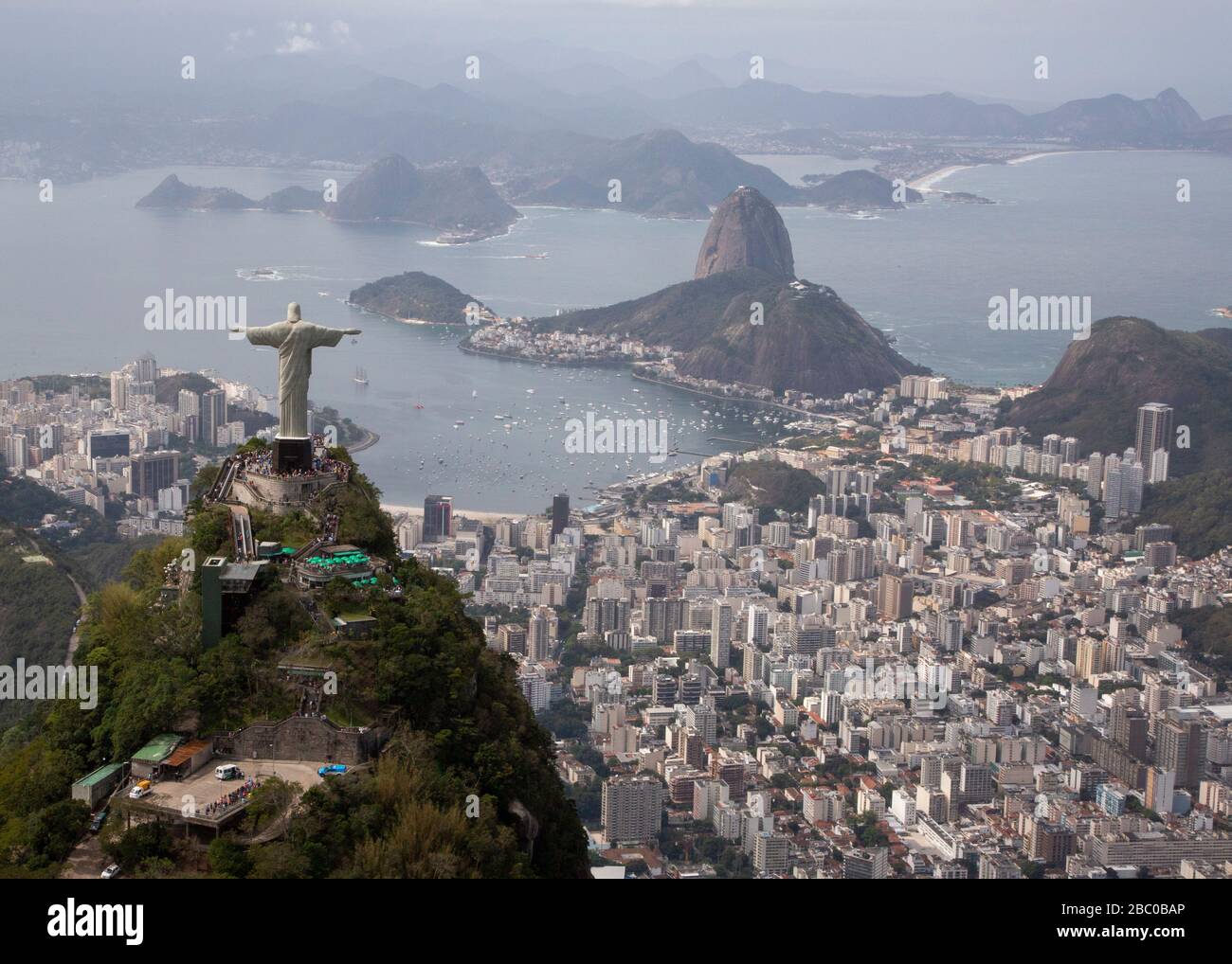 A view of Christ the Redeemer from above with a background of Botafogo bay and the Sugarloaf Mountain in Rio de Janeiro. Stock Photo