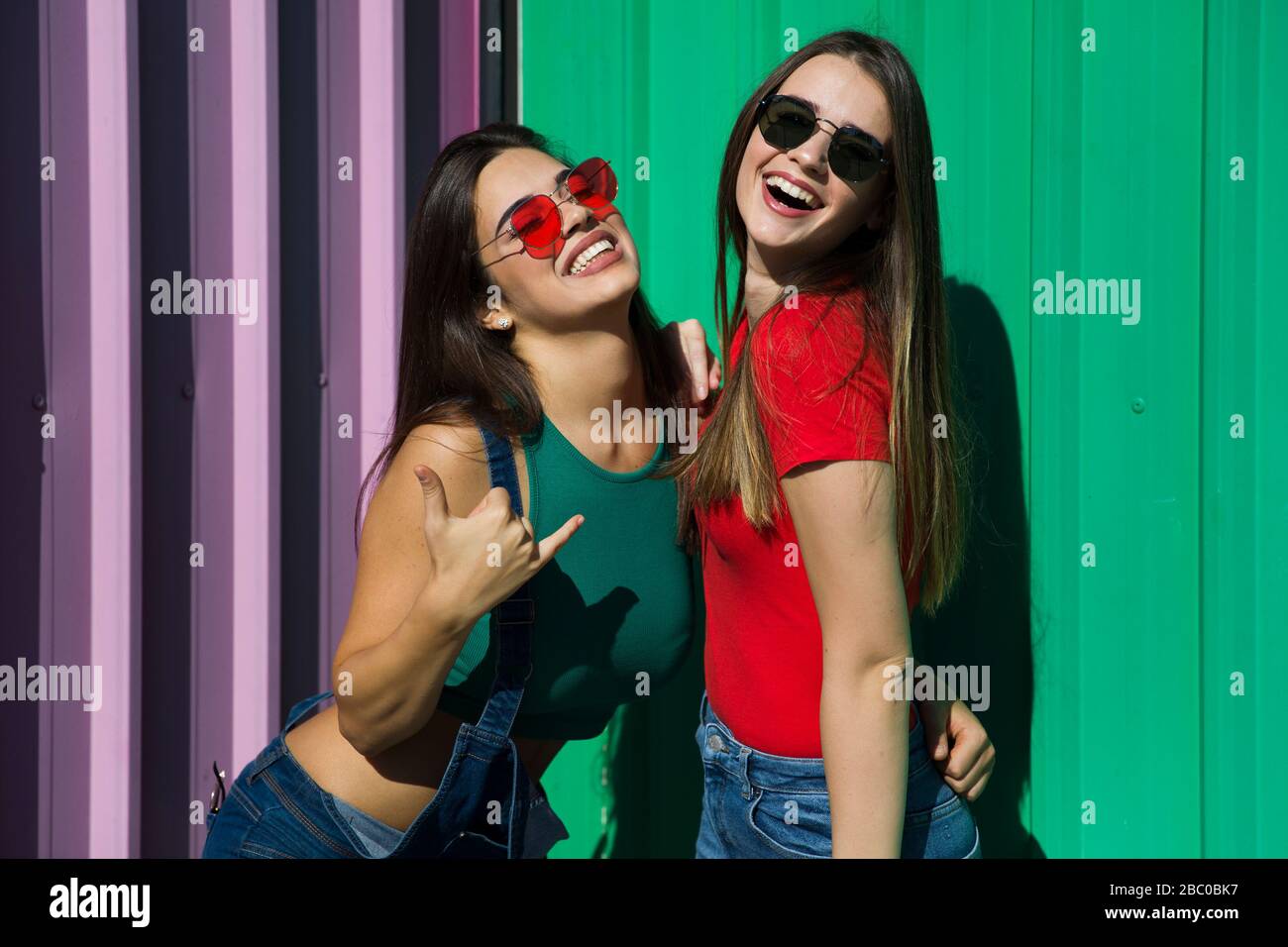 Two trendy young best female standing by the wall on a hot summer day Stock Photo