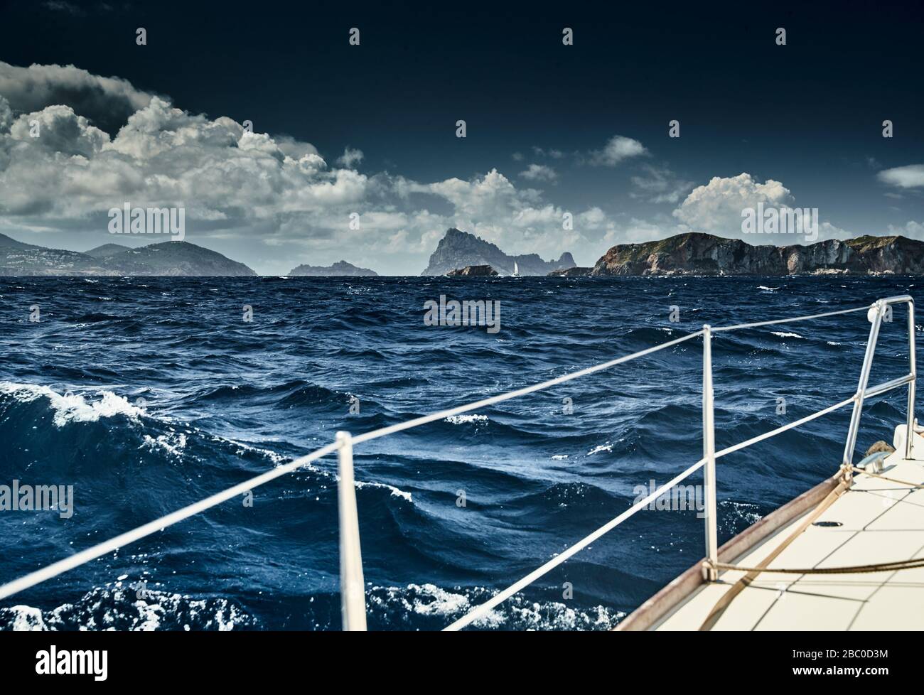 The view of the sea and mountains from the sailboat, edge of a board of the boat, slings and ropes, splashes from under the boat, sunny weather Stock Photo