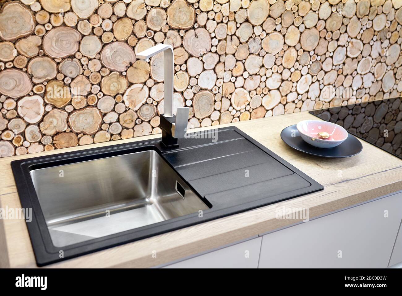 Modern design chrome water tap over stainless steel kitchen sink on table  top made of natural wood, with surface behind countertop decorated with  wall Stock Photo - Alamy