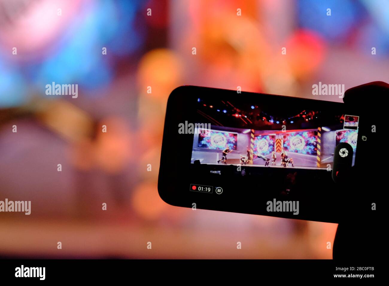 Person with iPhone in the audience filming performers on stage at Global Village, Dubai, United Arab Emirates. Stock Photo