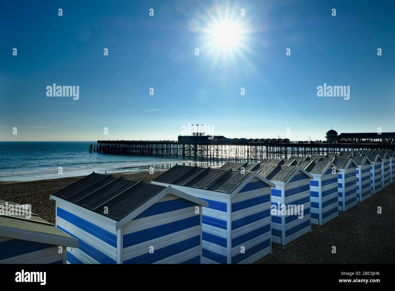 Row of beach huts on the beach next to the pier in Hastings, East Sussex, UK Stock Photo