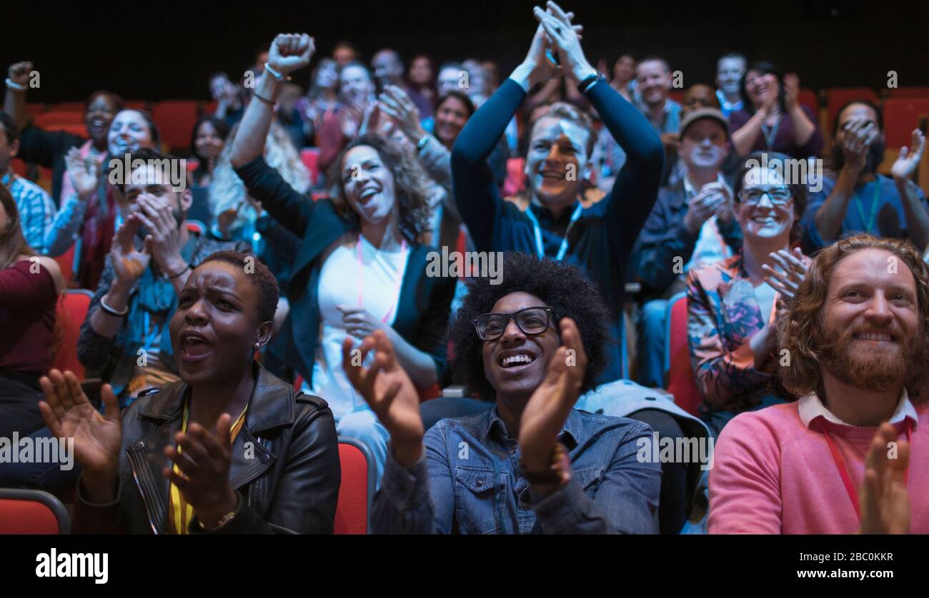 Excited audience clapping in dark room Stock Photo