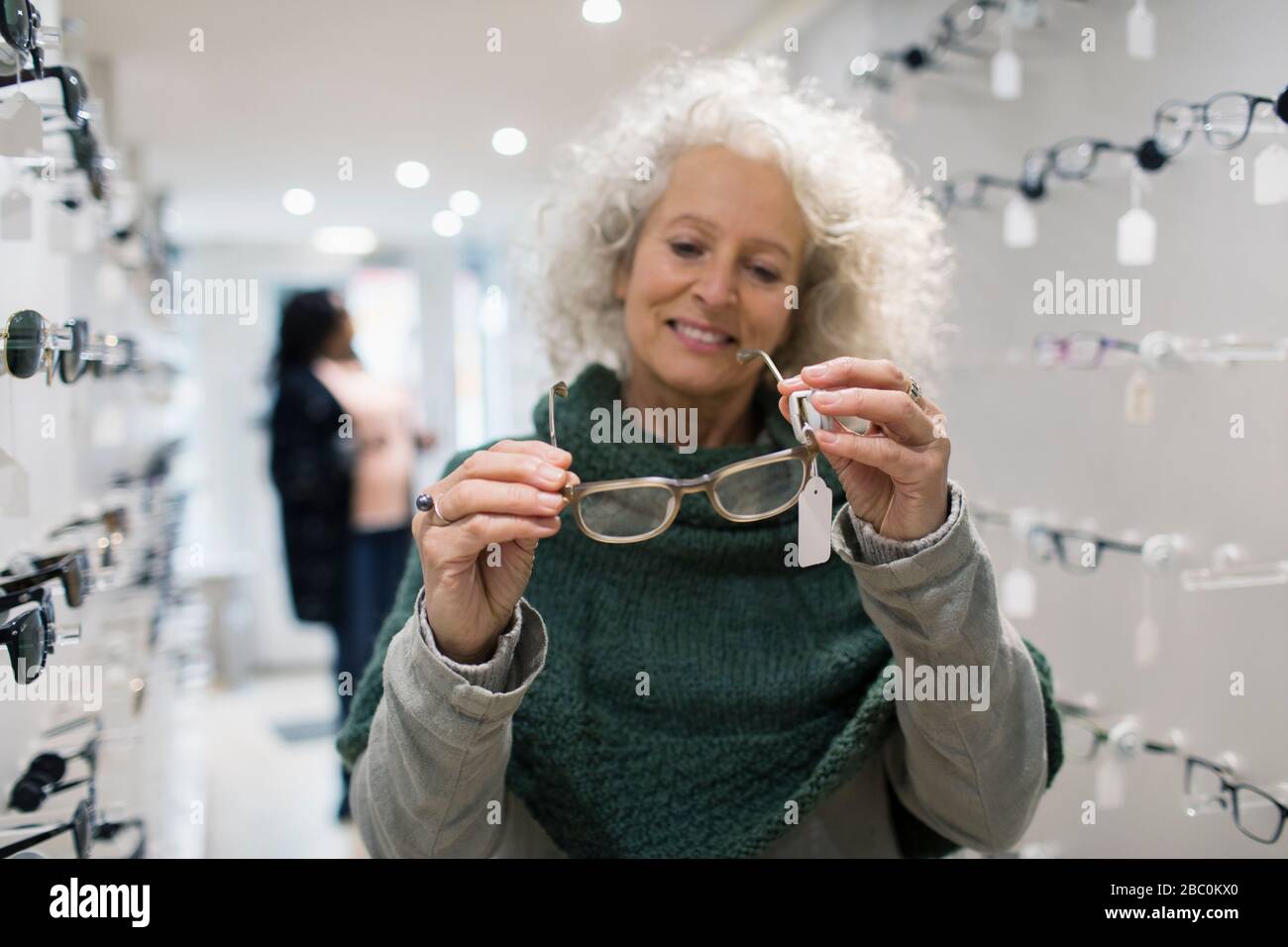 Senior woman shopping for eyeglasses in optometry shop Stock Photo