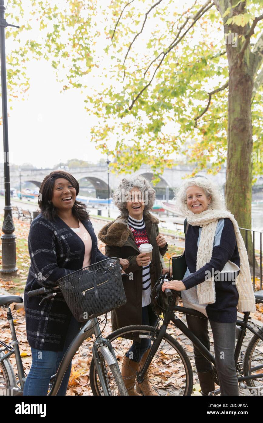 Portrait smiling, confident active senior women friends with coffee and bicycles in autumn park Stock Photo