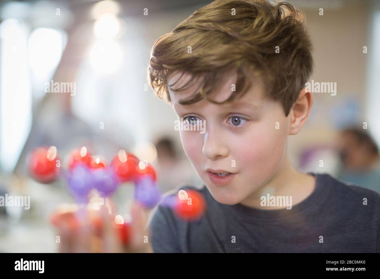 Curious boy examining molecule model in laboratory classroom Stock Photo