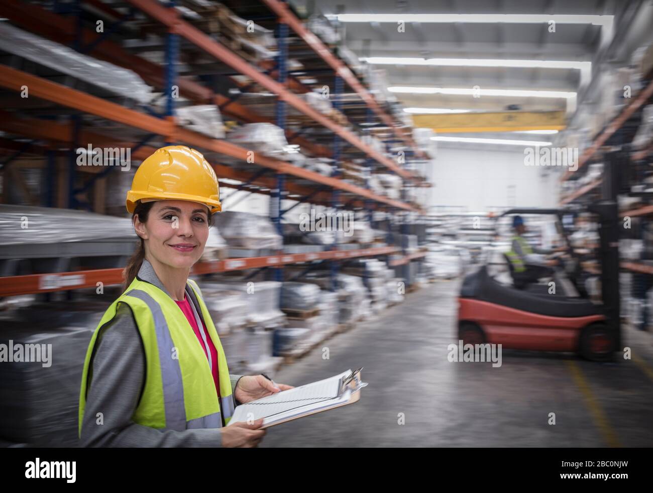 Portrait confident, smiling female worker with clipboard in warehouse Stock Photo