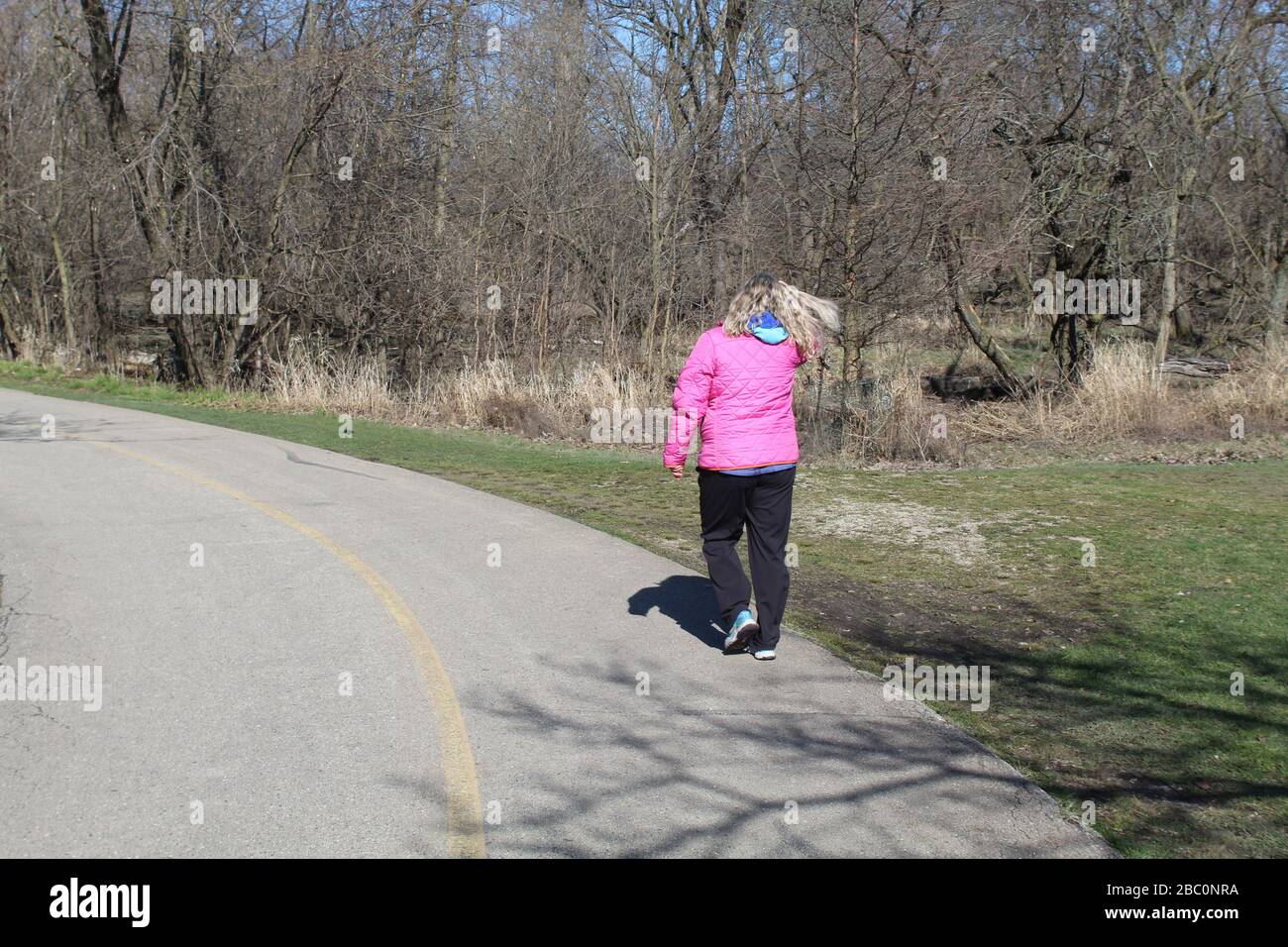Woman With Blonde Hair Blowing In The Wind In A Pink Coat On The North Branch Trail In Chicago 
