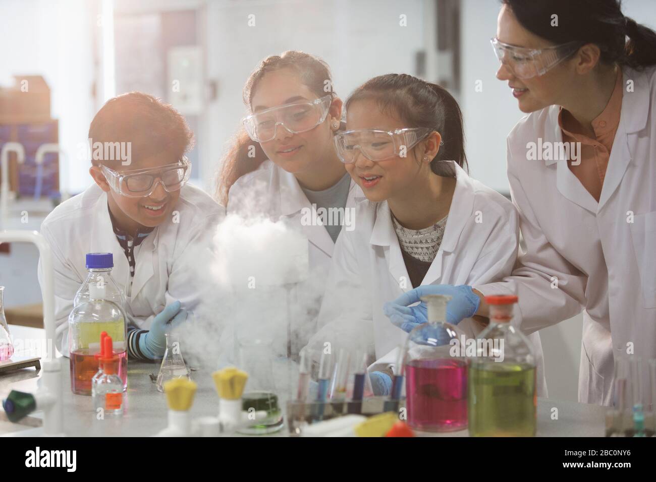Female teacher and students watching scientific experiment chemical reaction in laboratory classroom Stock Photo