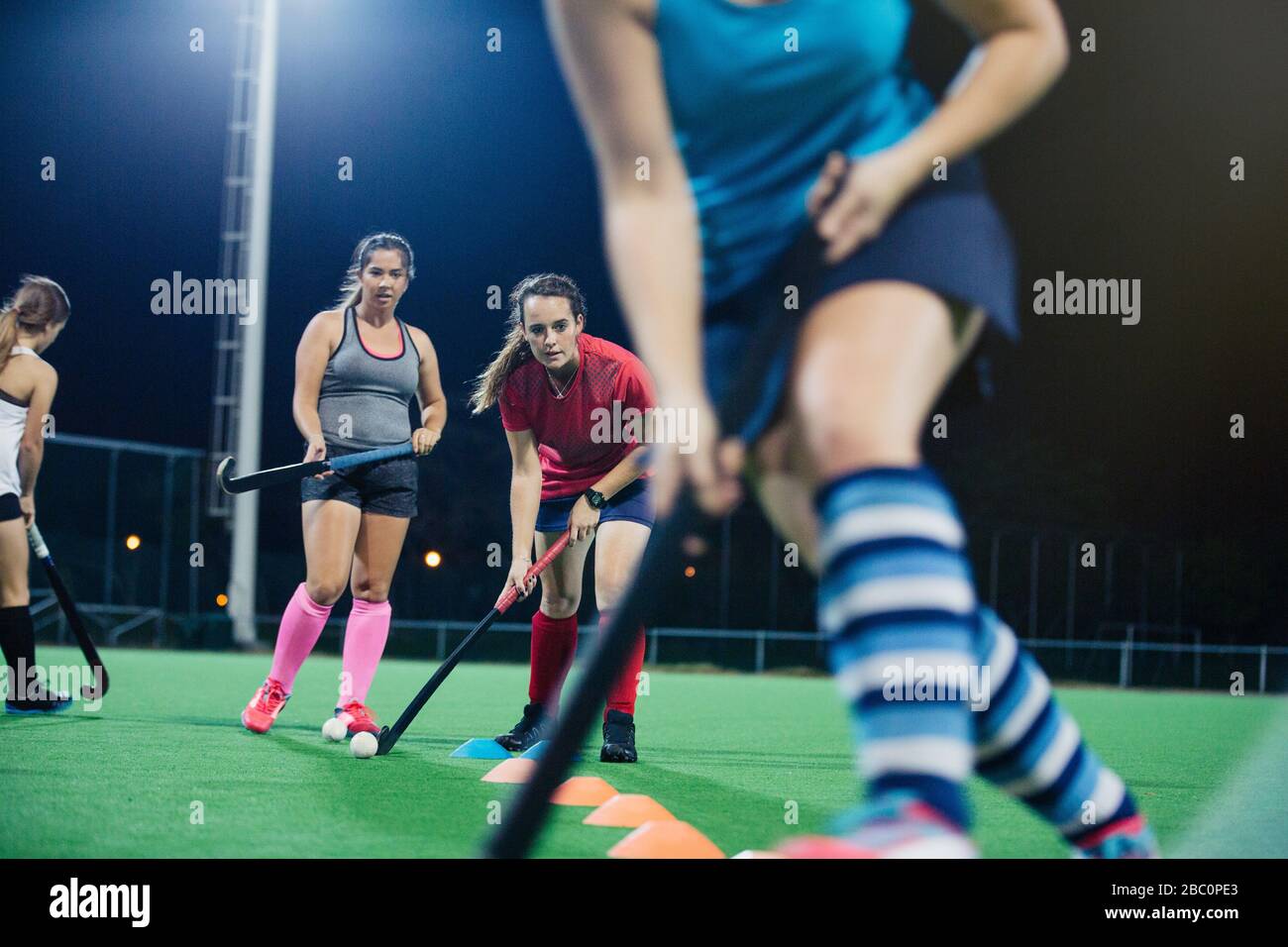 Young female field hockey players practicing sports drill on field