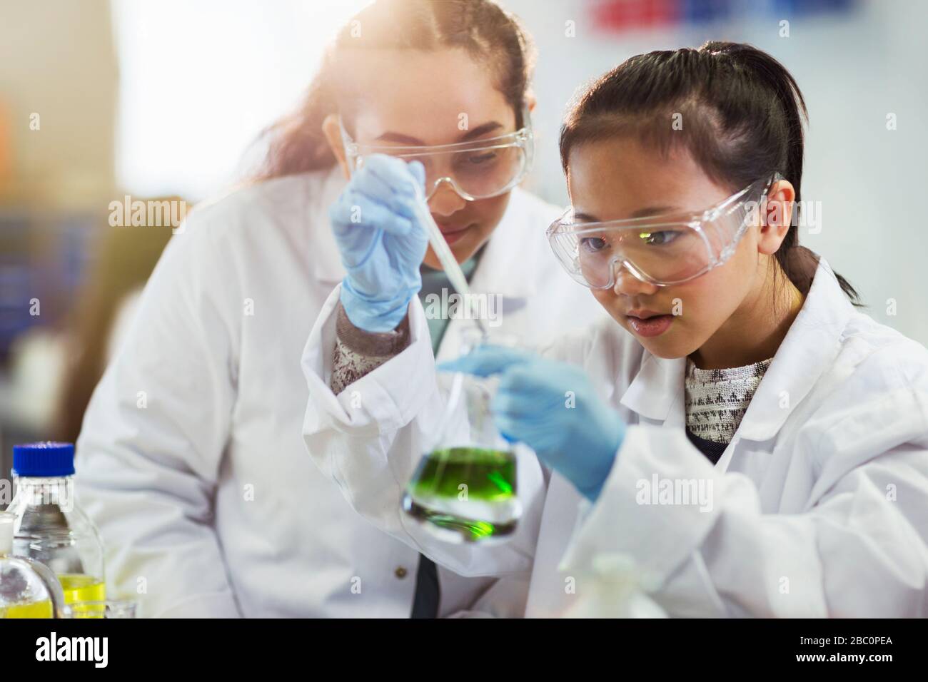 Girl students conducting chemistry experiment in classroom laboratory Stock Photo