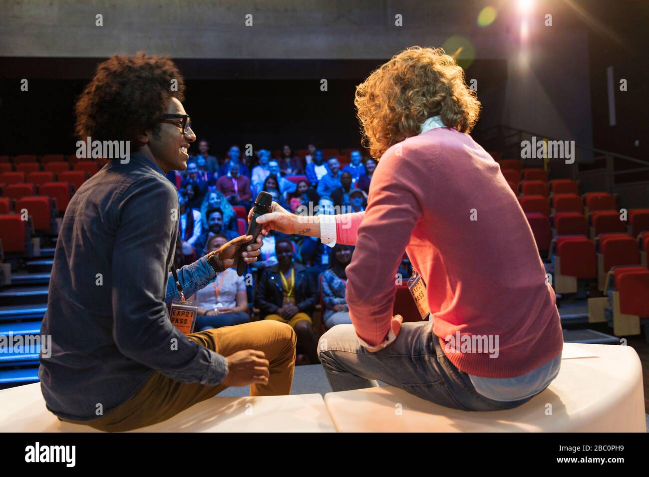 Speakers sharing microphone on conference stage Stock Photo Alamy