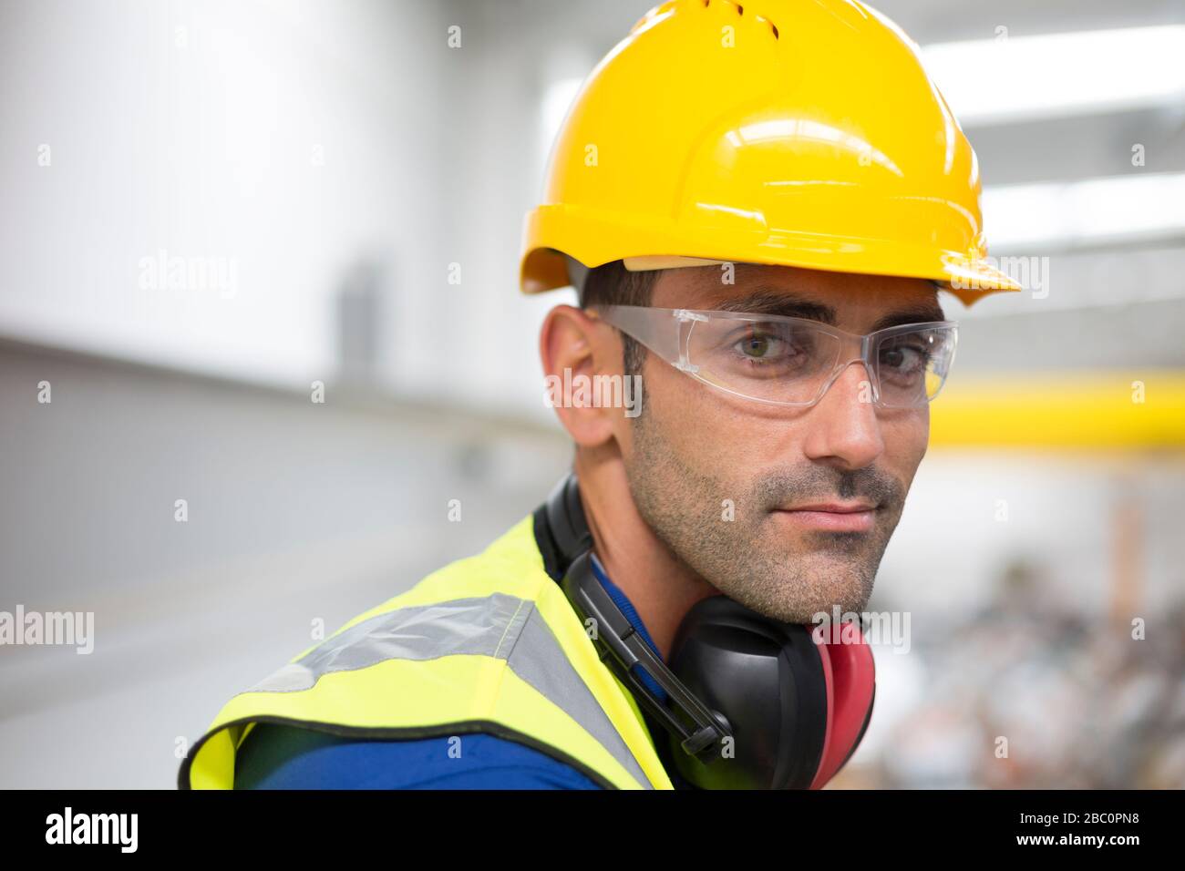 Portrait serious male worker in protective eyewear and hard-hat in factory Stock Photo