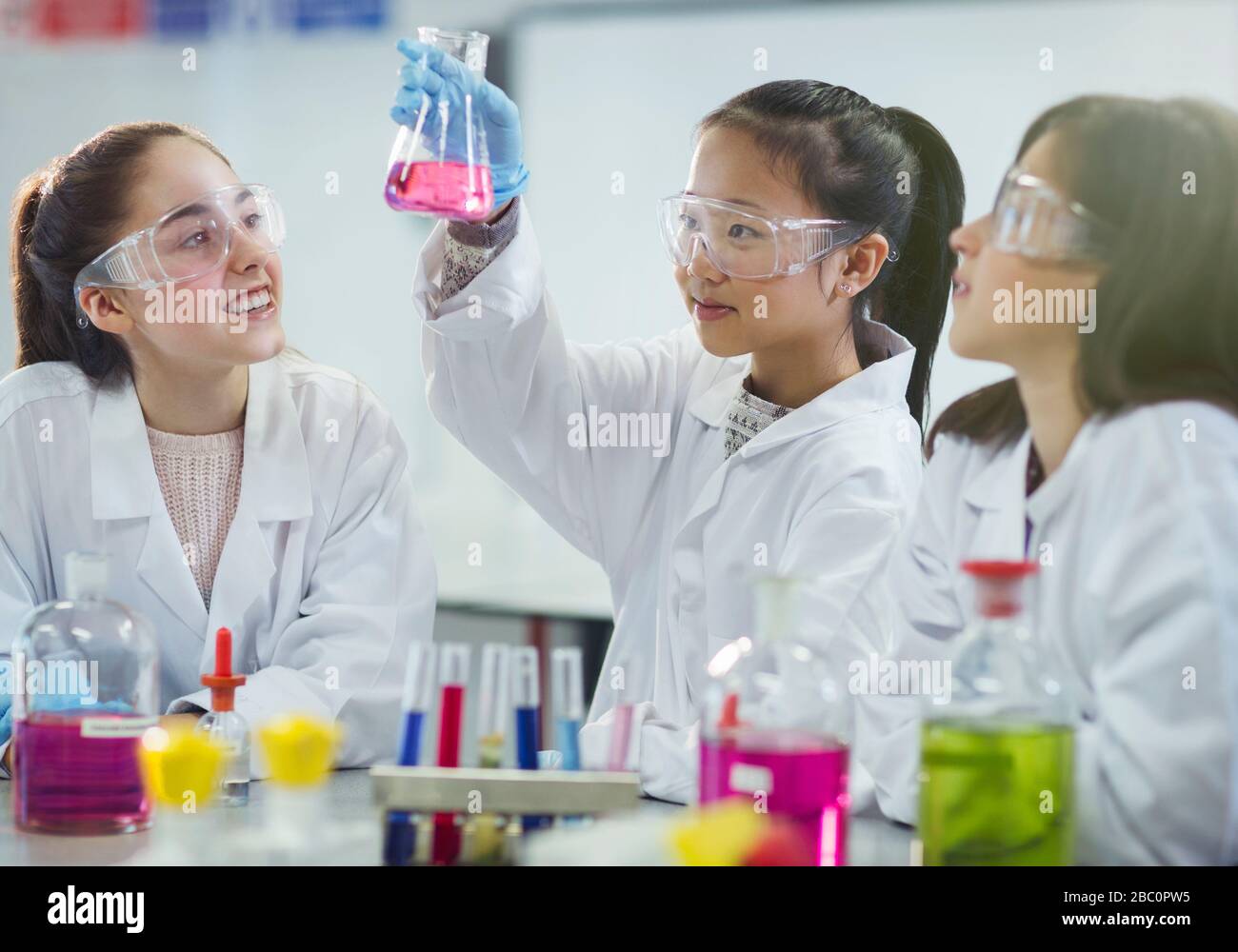 Girl students conducting scientific experiment in chemistry laboratory classroom Stock Photo