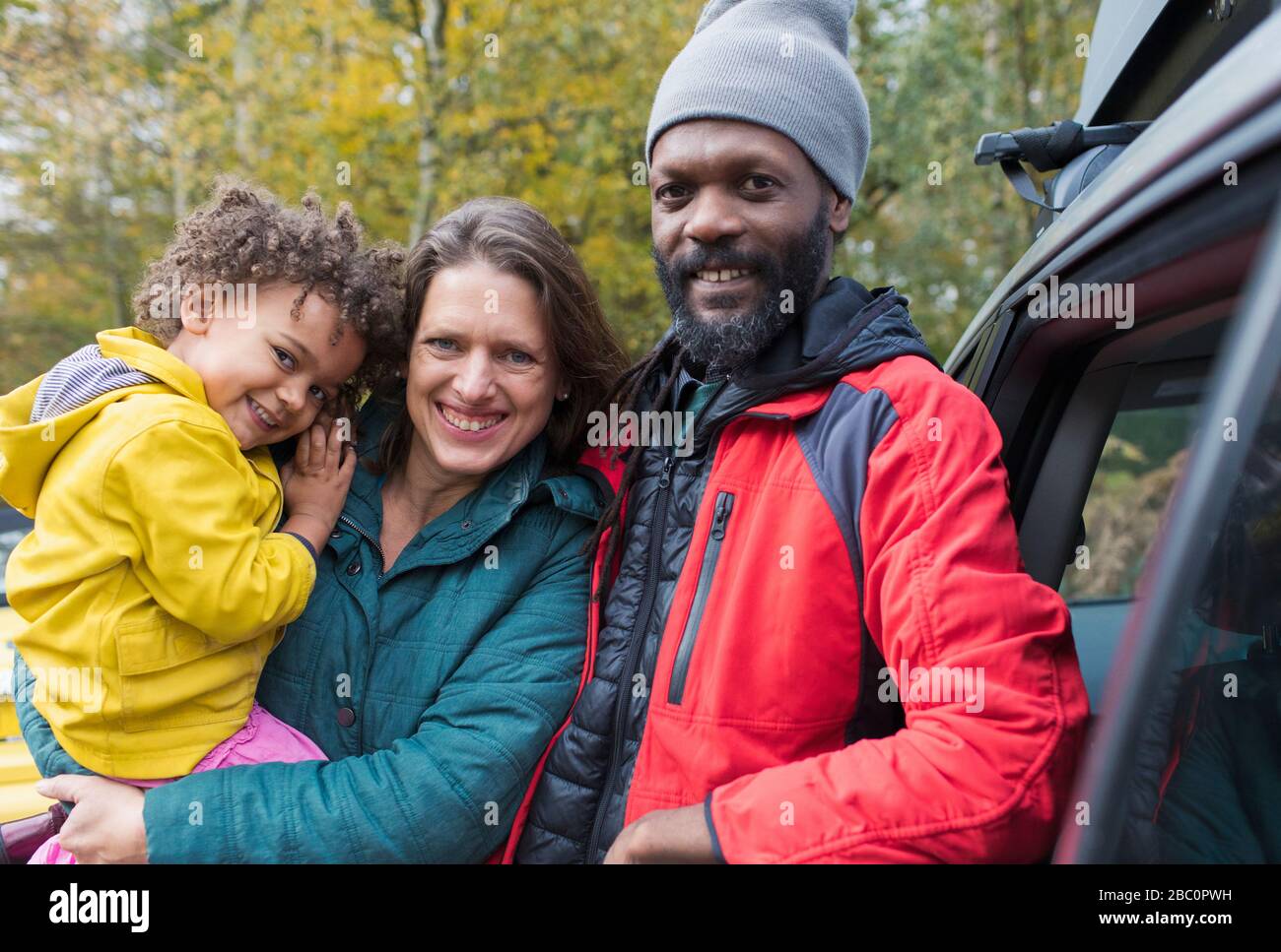 Portrait happy multiethnic family standing outside car Stock Photo