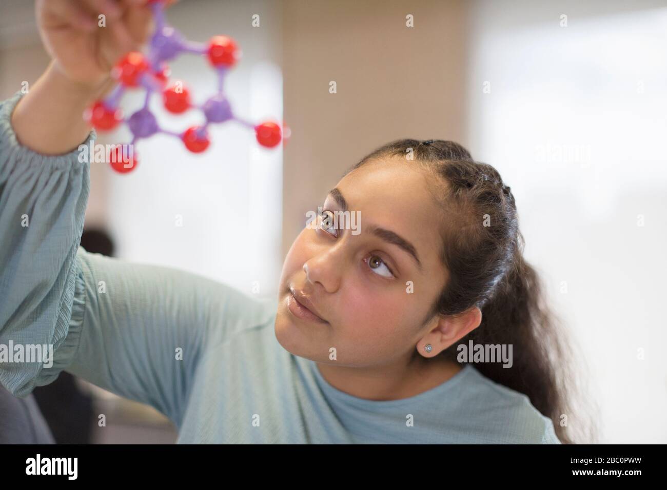 Curious girl student examining molecular structure in classroom Stock Photo