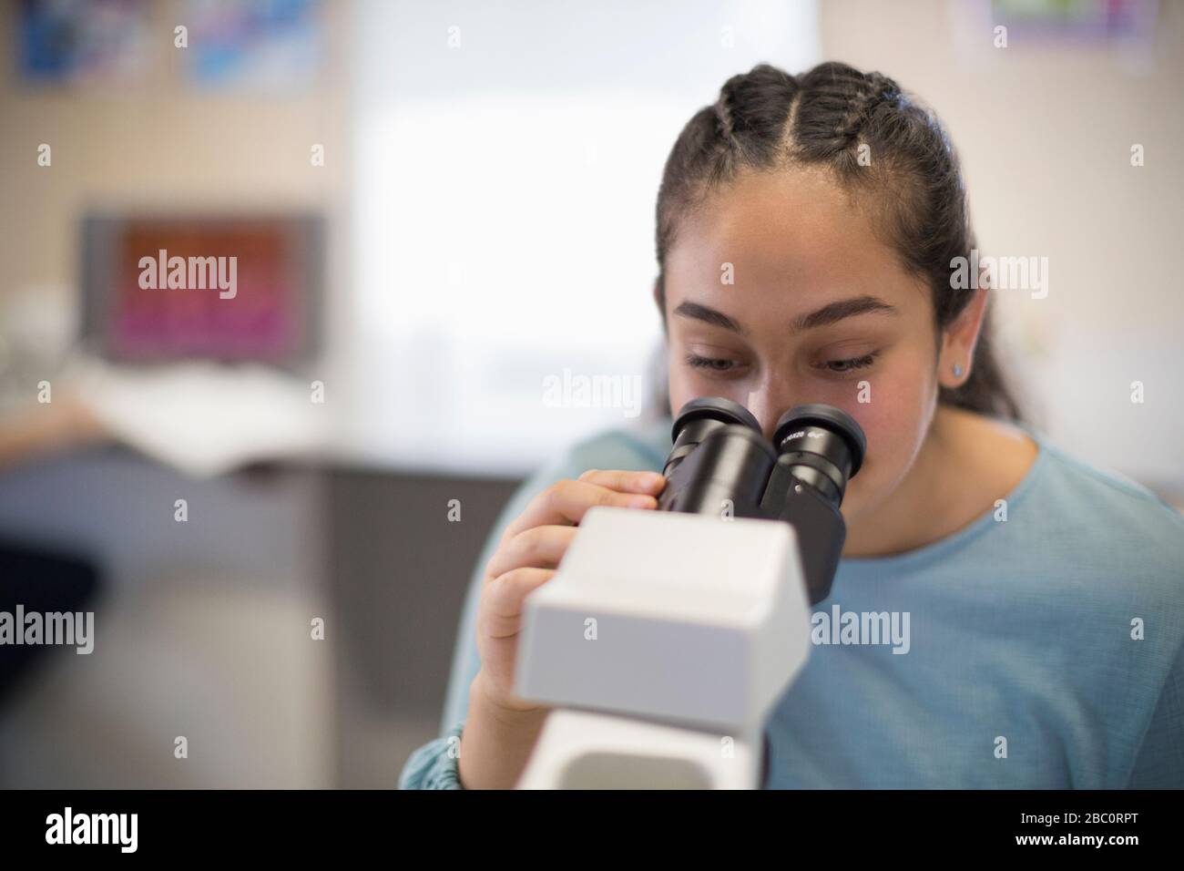 Girl student using microscope in classroom Stock Photo