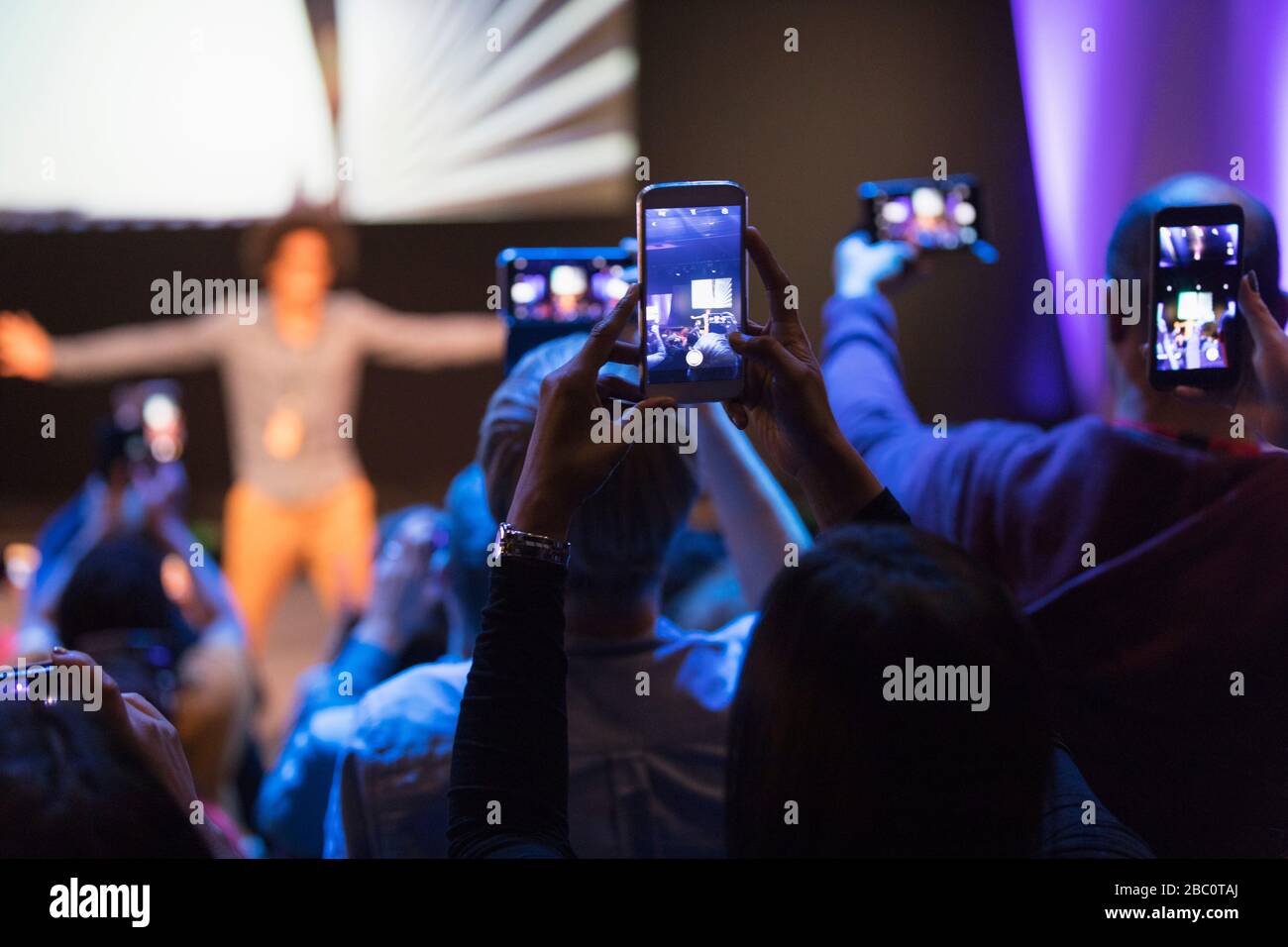 Audience with camera phones photographing speaker on stage Stock Photo