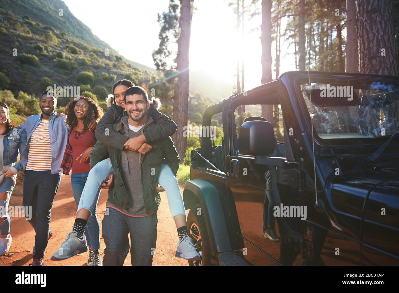 Portrait playful young friends enjoying road trip outside jeep Stock Photo