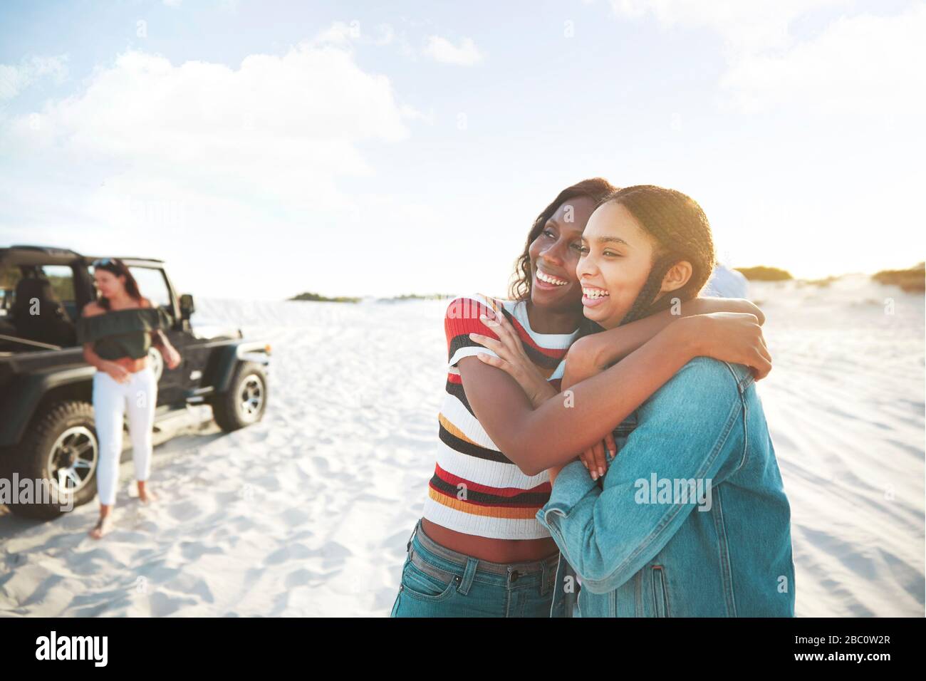 Happy young women friends hugging, enjoying beach road trip Stock Photo