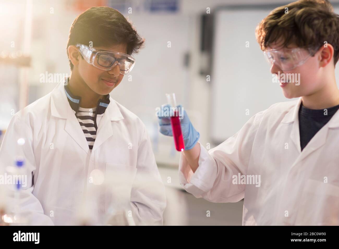 Boy students examining liquid in test tube, conducting scientific