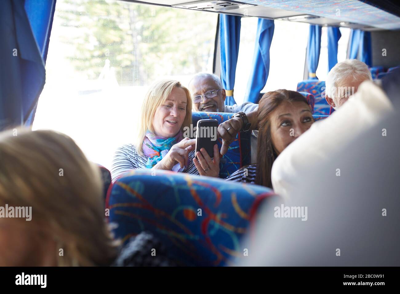 Active senior women tourists using smart phone on tour bus Stock Photo