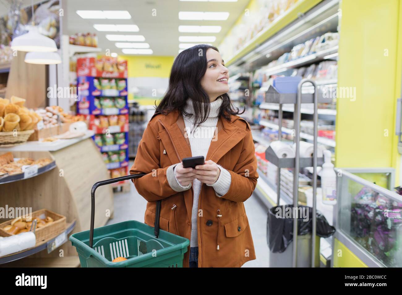 Woman with smart phone shopping in supermarket Stock Photo