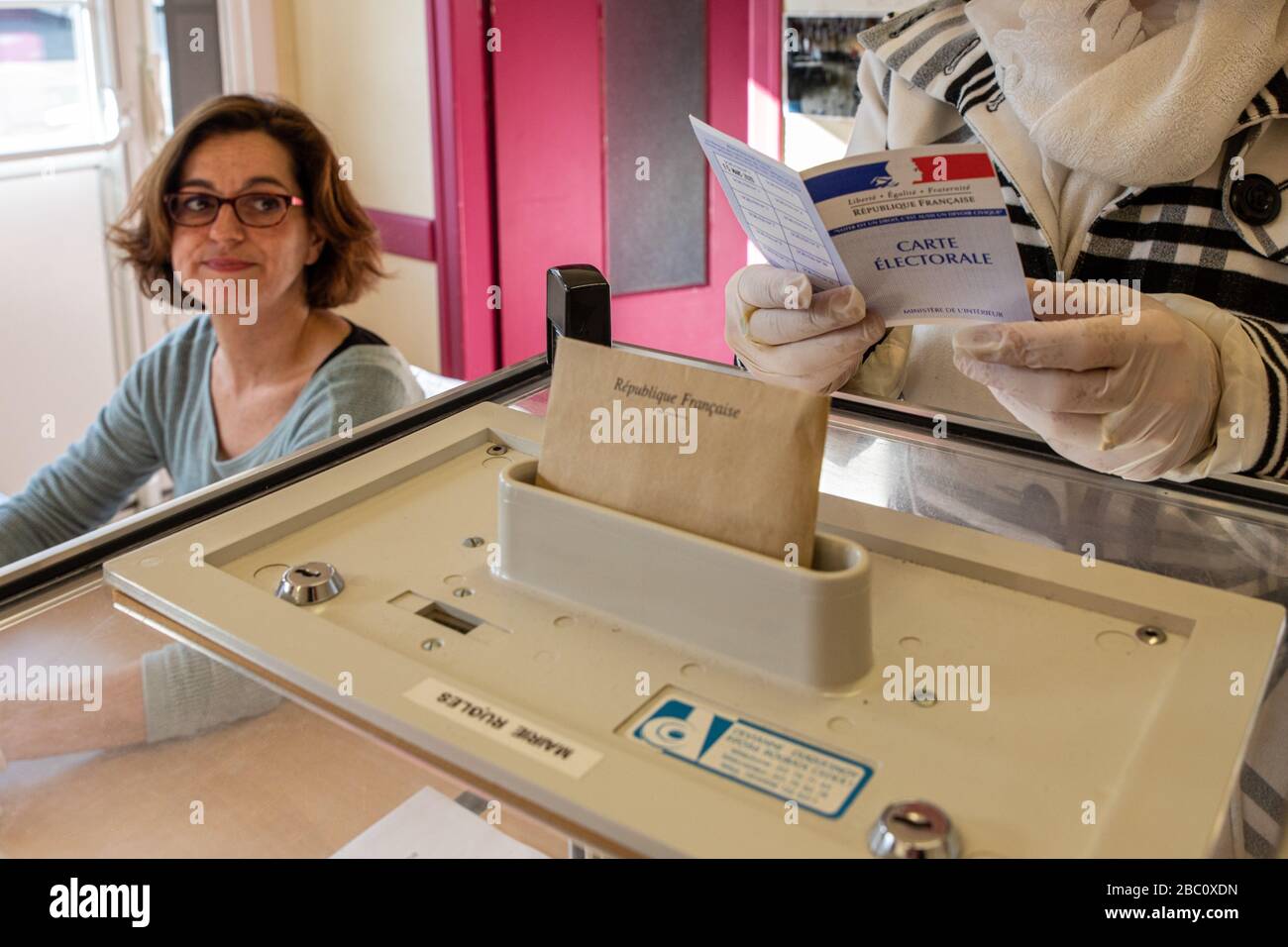 VERIFICATION OF THE VOTER'S CARD BFORE THE VOTE, DURING THE FIRST ROUND OF THE MUNICIPAL ELECTIONS WHILE RESPECTING THE HEALTH MEASURES TAKEN IN LIGHT OF THE CORONAVIRUS PANDEMIC, VOTING STATION IN RUGLES, NORMANDY, FRANCE Stock Photo