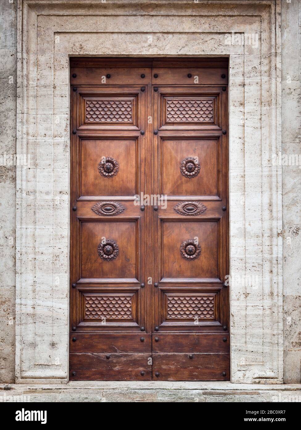 Wooden door of an ancient romanesque church with carved flowers. Stock Photo